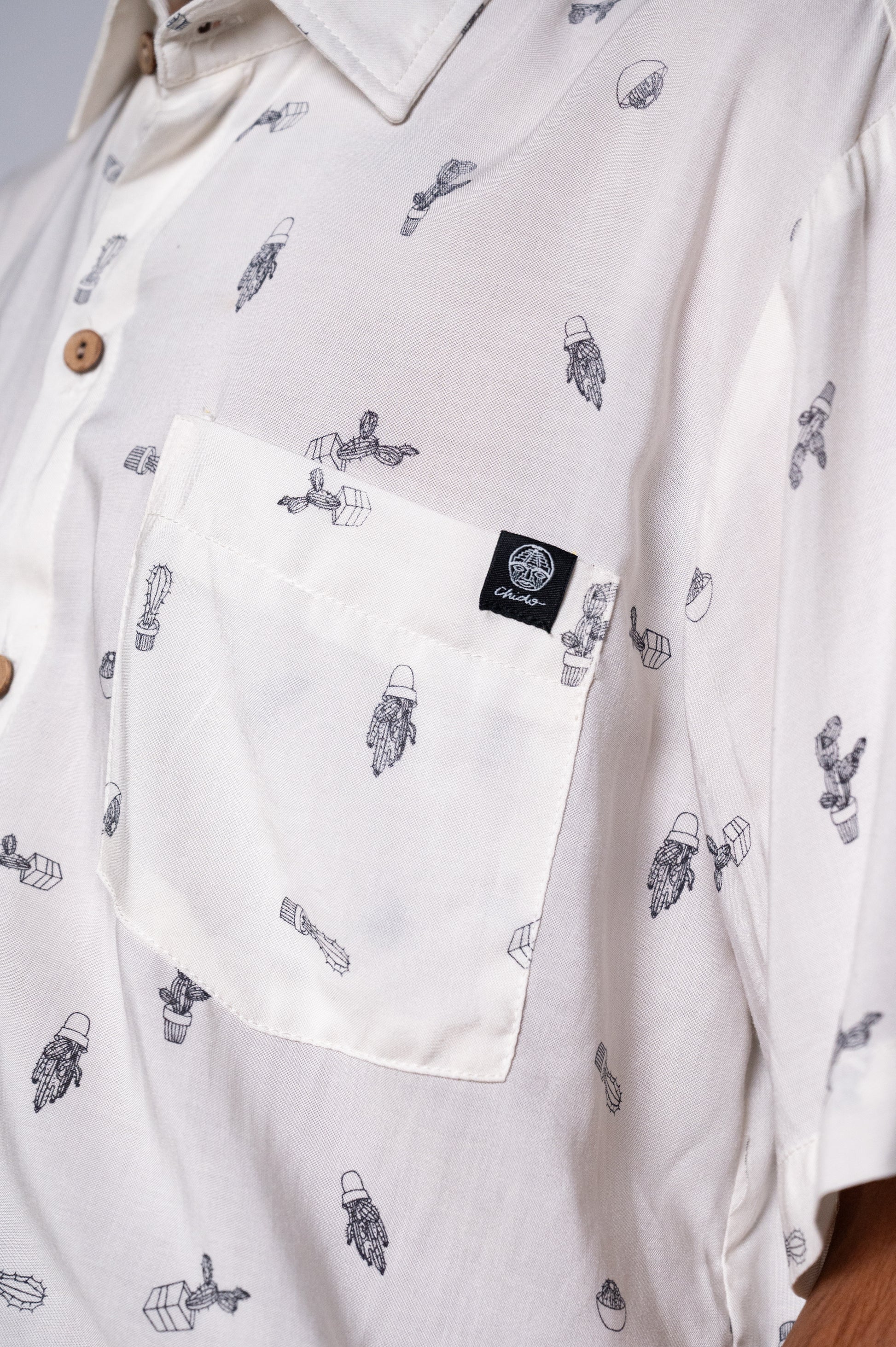 Camisa Oversize Chido de corte oversize confeccionada en rayón, un tejido ligero y fresco que garantiza comodidad. Presenta un diseño blanco con estampados minimalistas de cactus y elementos botánicos que evocan la cultura mexicana y un estilo relajado y auténtico. Los botones en coco le aportan un toque natural y elegante, mientras que su silueta amplia es ideal para un look casual y moderno.